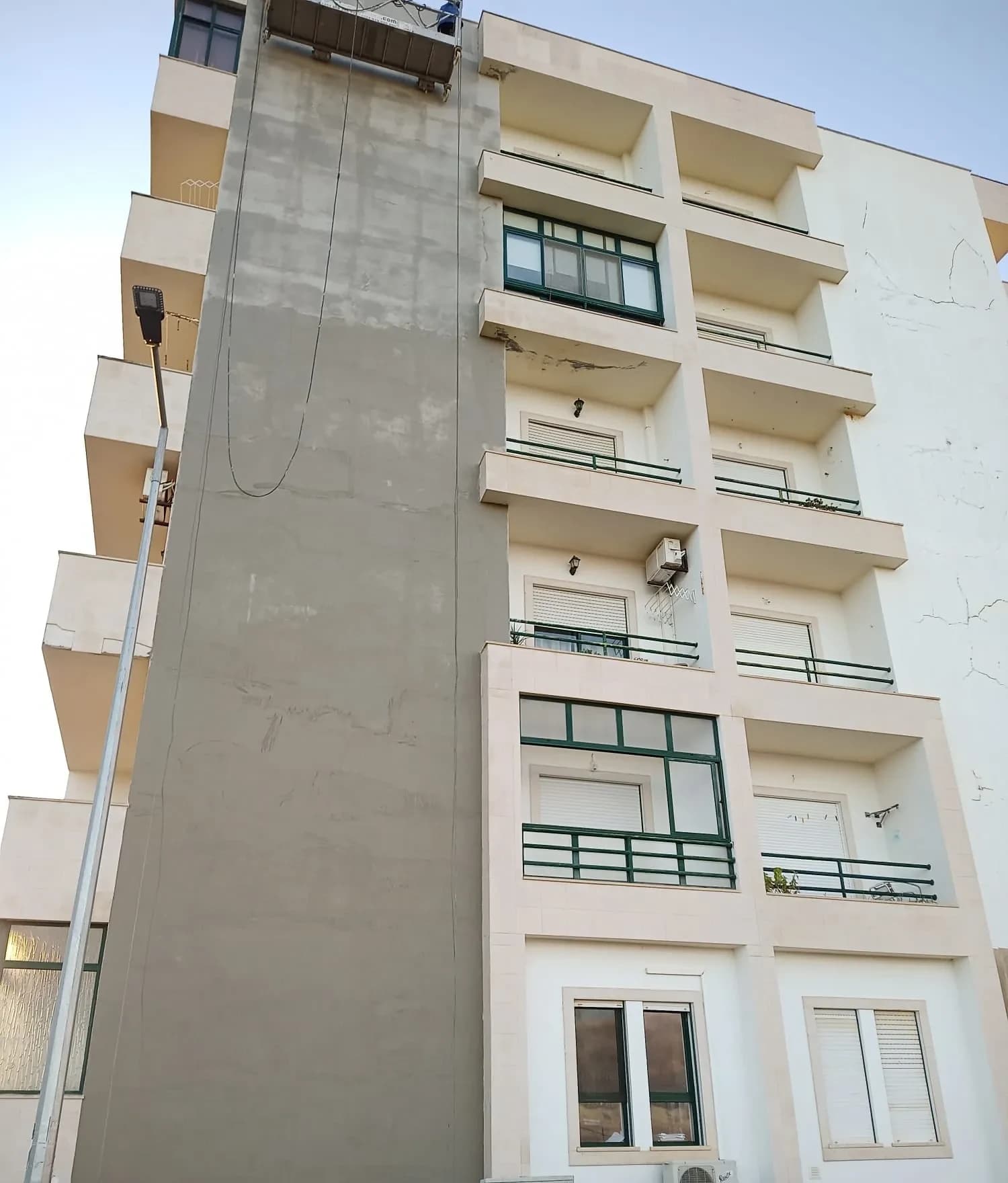 Fachada de um prédio em reabilitação, com reboco novo aplicado.